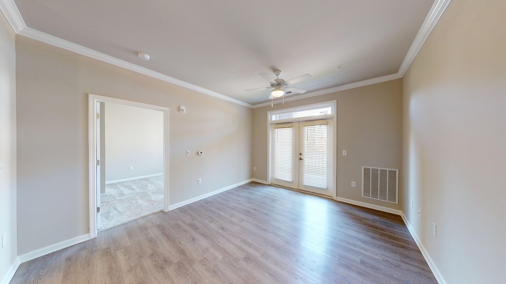 an empty living room with a ceiling fan and window