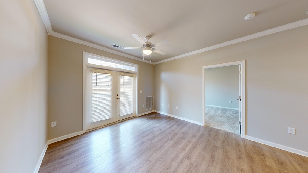 an empty living room with wood floors and a ceiling fan