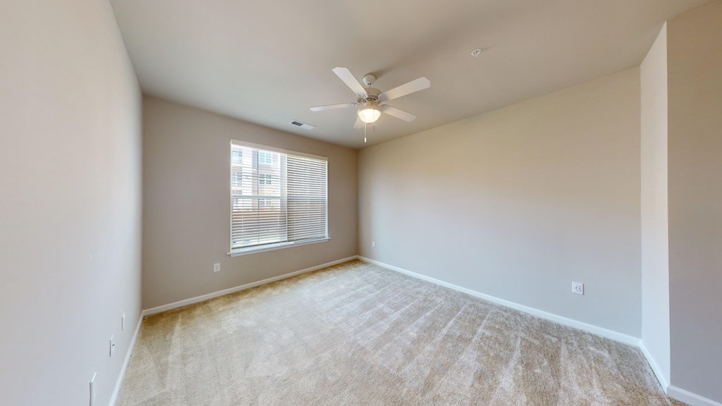 an empty living room with a ceiling fan and a window