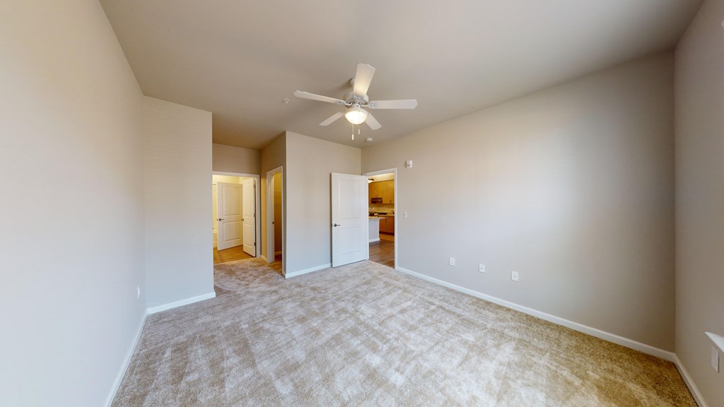 a spacious living room with carpet and a ceiling fan
