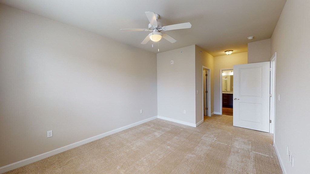 Bedroom with ceiling fan, carpet and door to bathroom