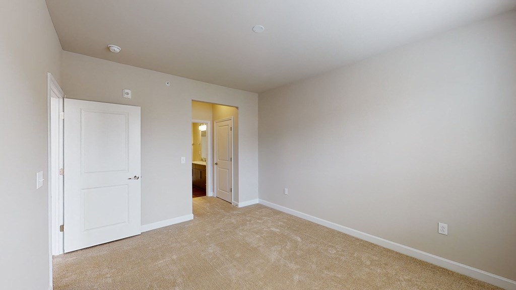 Bedroom with carpet; door to bathroom