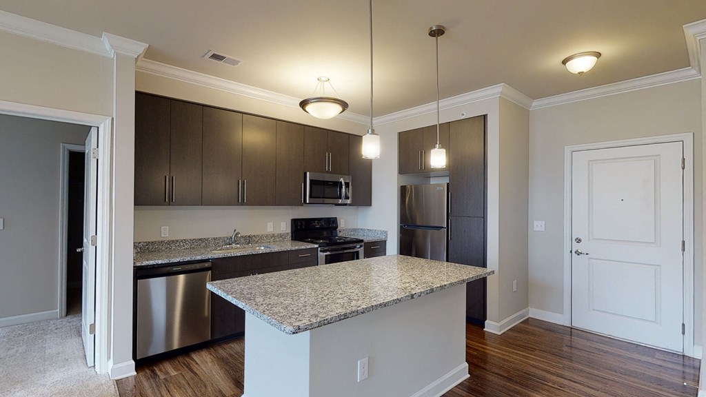 Kitchen with island, dark cabinets, vinyl floors and granite countertops