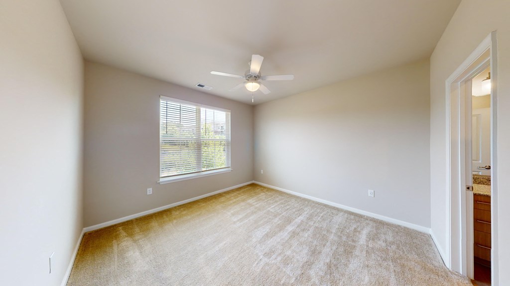 an empty living room with a ceiling fan and a window