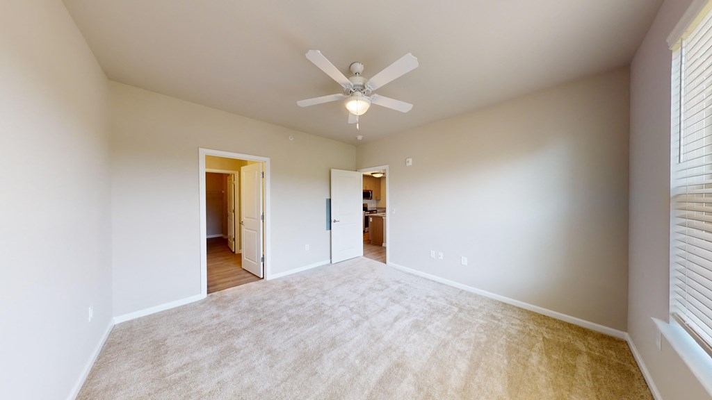 a spacious living room with a ceiling fan and a carpet
