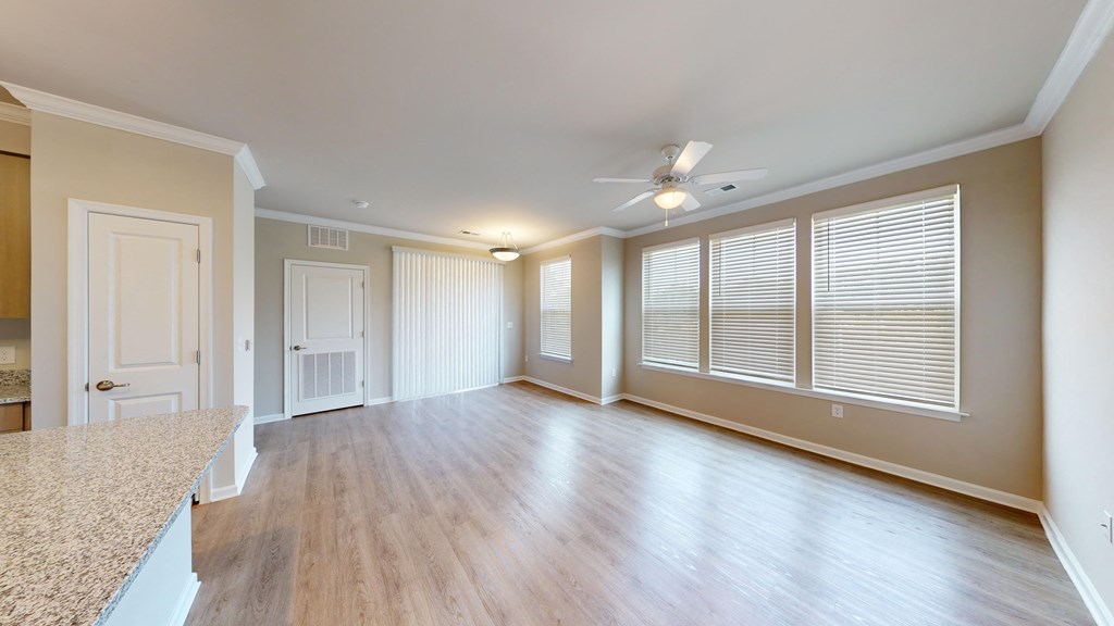 an empty living room with a large window and a ceiling fan