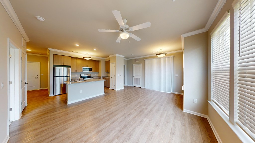an empty living room with a ceiling fan and a kitchen