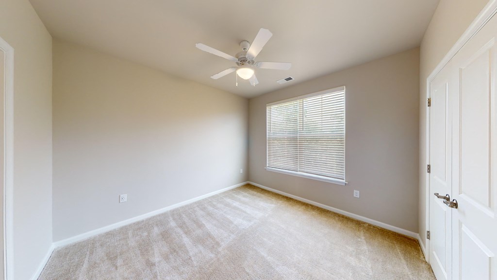 an empty room with a ceiling fan and a window