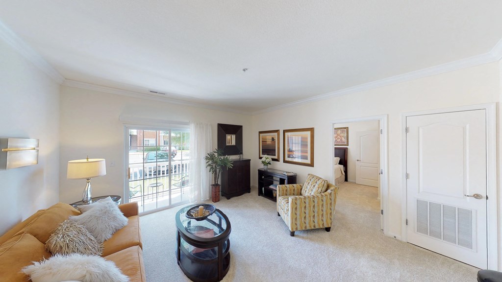 Living room with couch and chair; door to patio or balcony