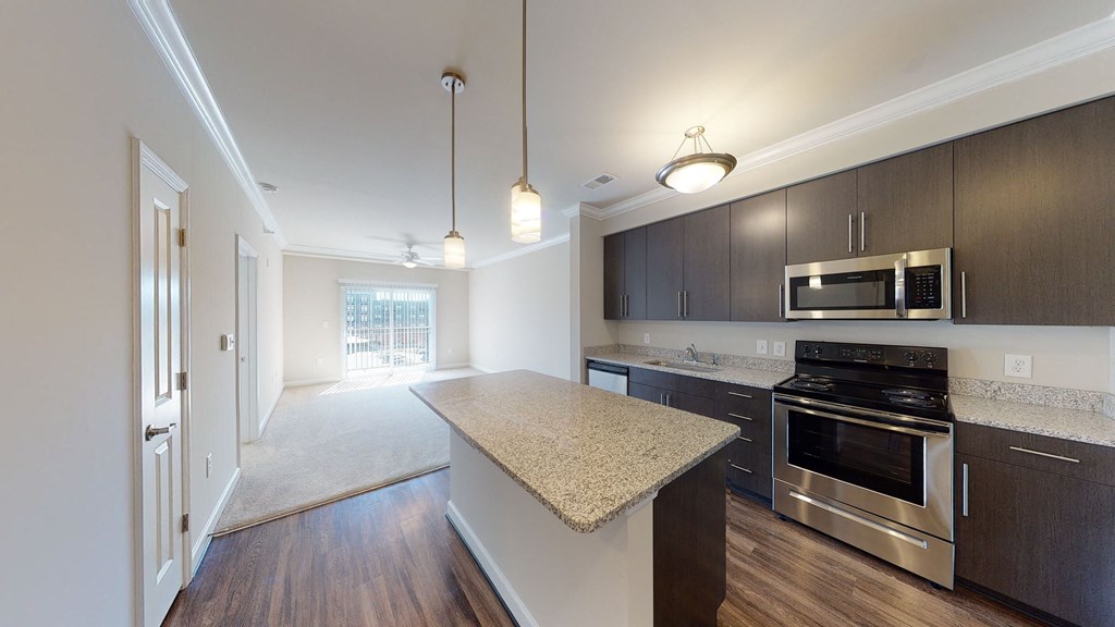 Kitchen with brown cabinets, stainless steel appliances and granite countertops; open to living room