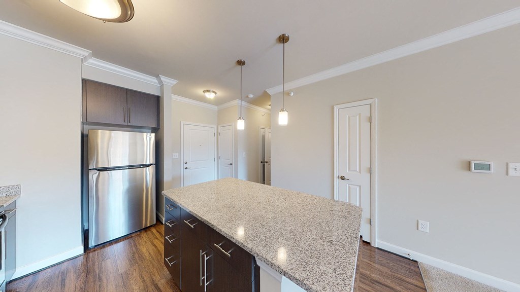 Kitchen with island, dark cabinets, vinyl floors and granite countertops