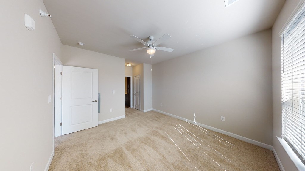 Bedroom with ceiling fan, carpet and door to bathroom