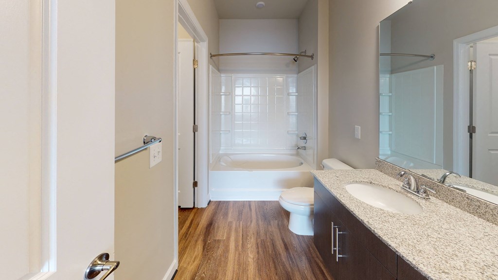 Bathroom with sink, toilet, shower and tub; dark cabinets, vinyl floors