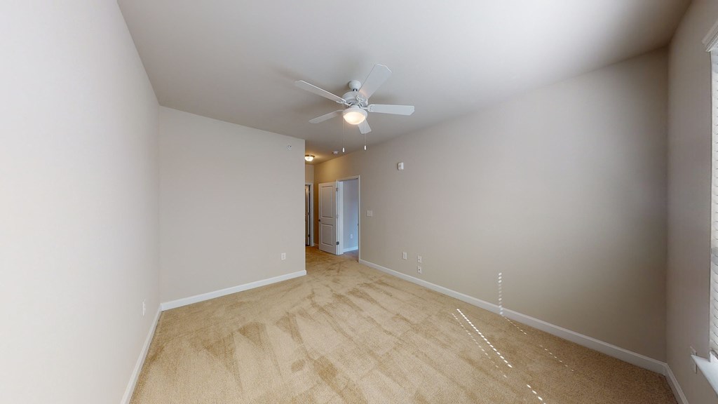 Bedroom with ceiling fan, carpet and door to bathroom