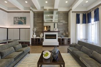 Clubhouse with chairs and fireplace; windows overlooking the pool