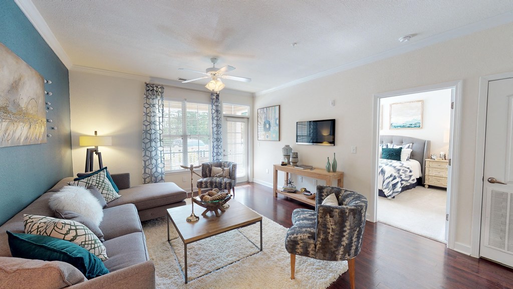 Living room with couch and chair; door to patio or balcony; ceiling fan