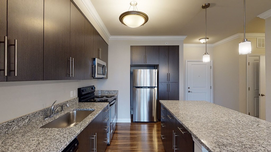 Kitchen with dark cabinets, granite countertops, vinyl wood plank floors