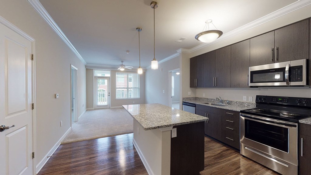 Kitchen with island, dark cabinets and granite countertops; open to the main living area