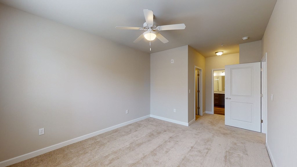 Bedroom with ceiling fan, carpet and door to bathroom