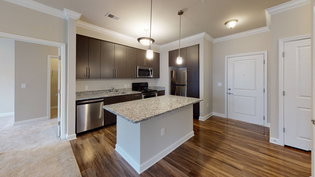 Kitchen with island, dark cabinets, vinyl floors and granite countertops