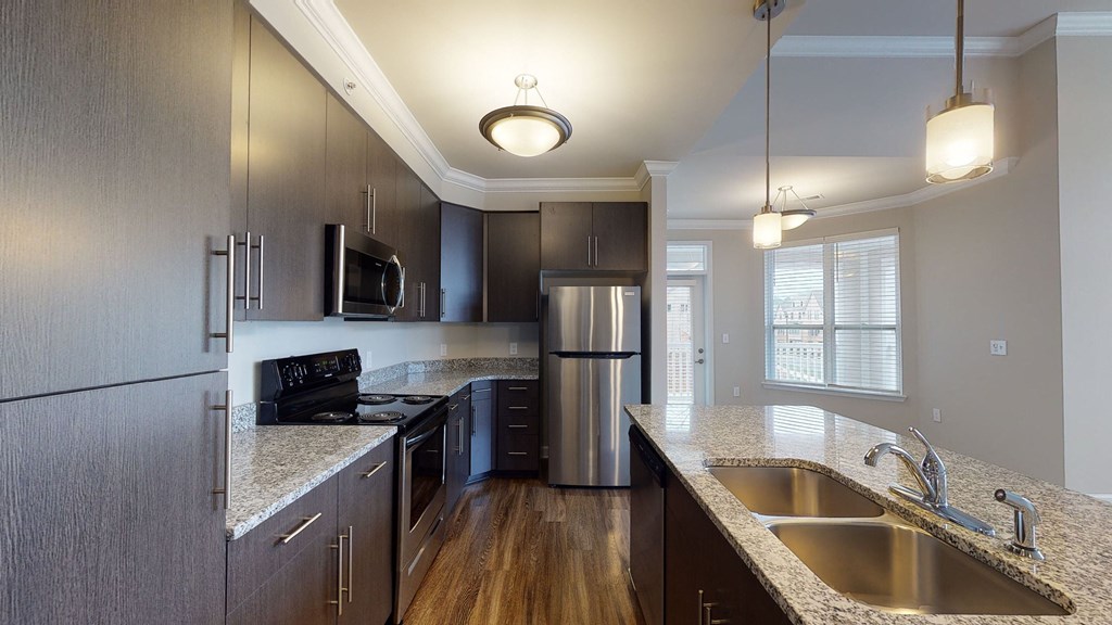 Kitchen with island, dark cabinets, vinyl floors and granite countertops