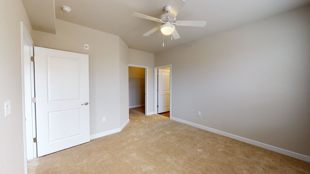 Bedroom with ceiling fan, carpet and door to bathroom