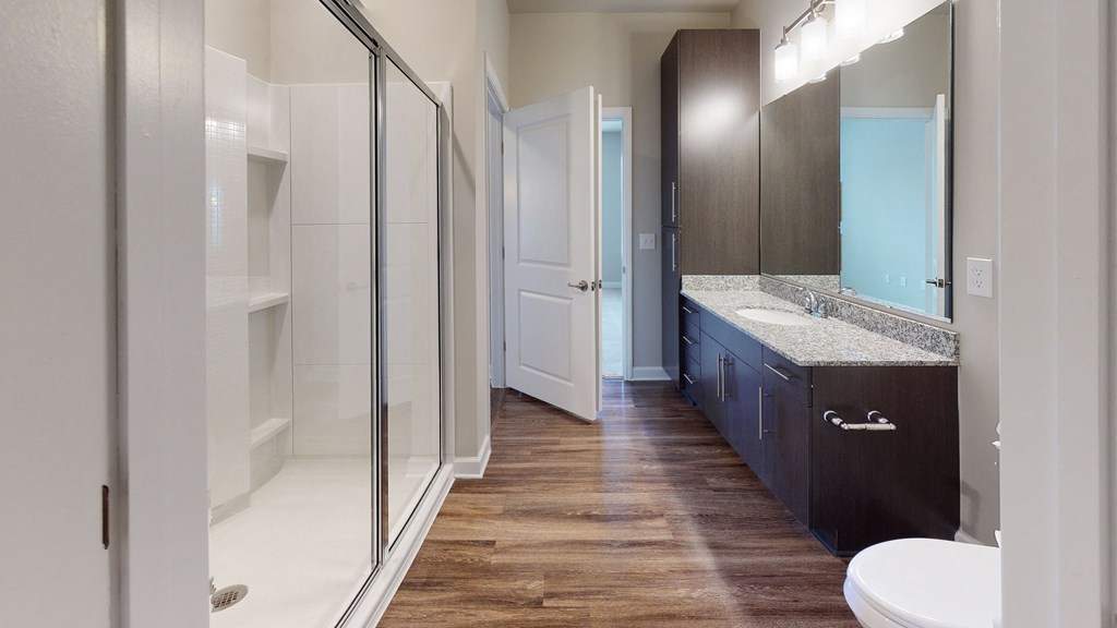Bathroom with shower, dark cabinets, vinyl floors
