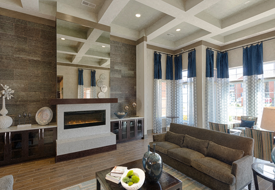 Clubhouse with chairs and fireplace; windows overlooking the pool