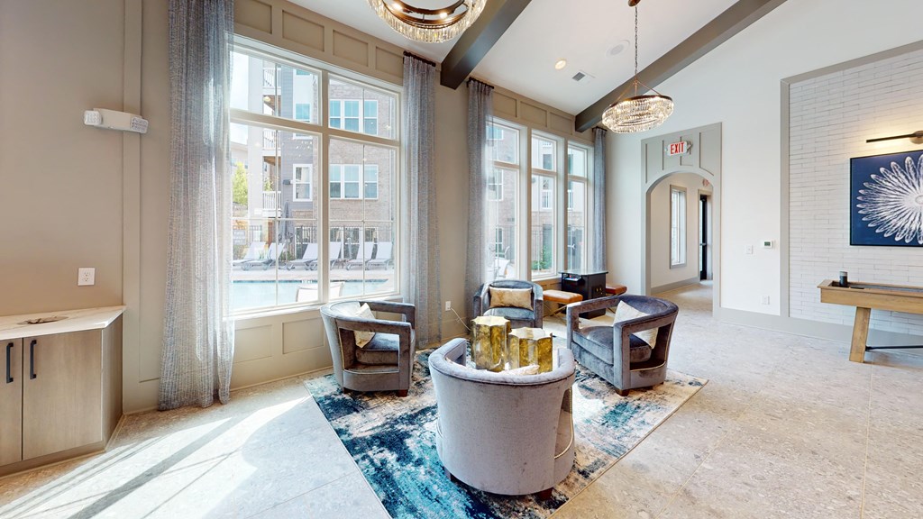 a living room with couches and chairs and large windows