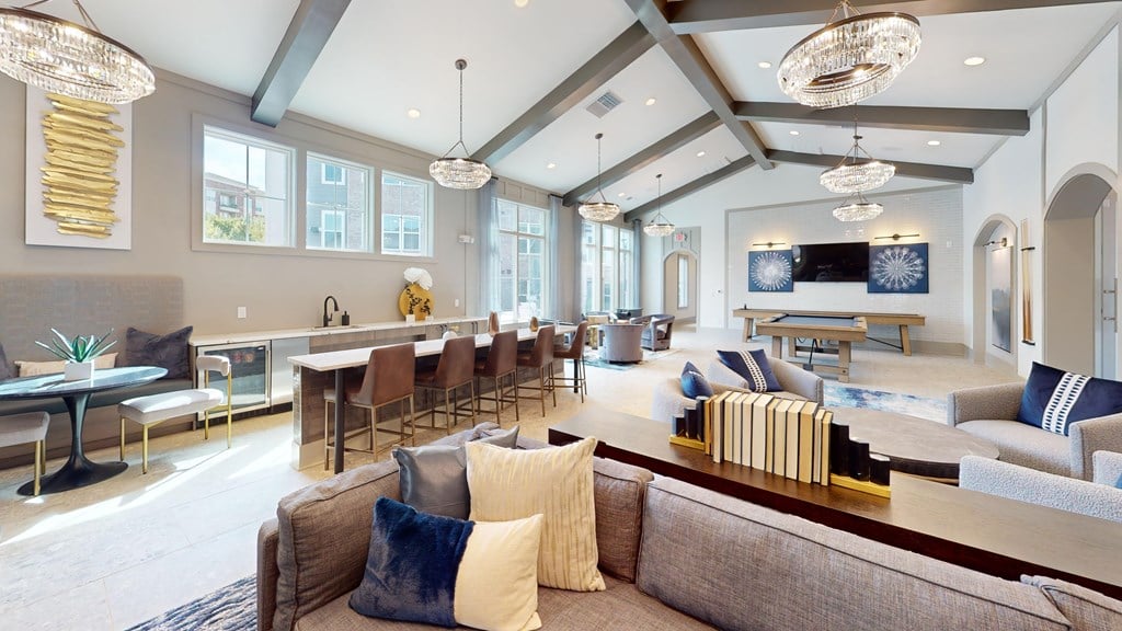 A large, well-lit living room with a variety of seating options and decorative pillows.