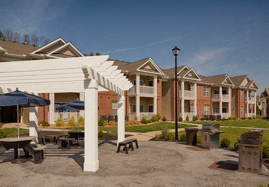 Grilling area with picnic tables and umbrellas under a pergola
