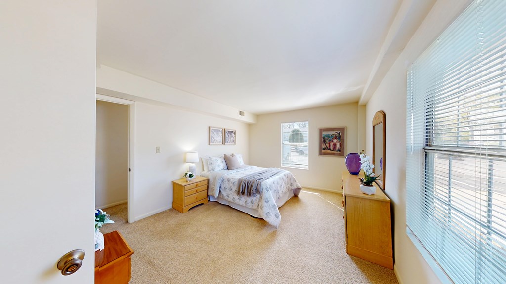 A bedroom with a bed, nightstand, and window.