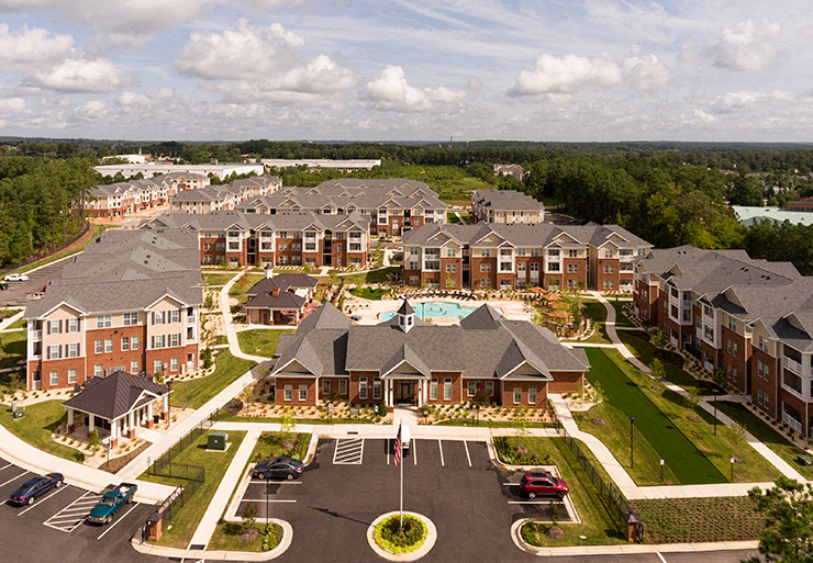 Aerial view of community clubhouse, parking lot and apartment buildings