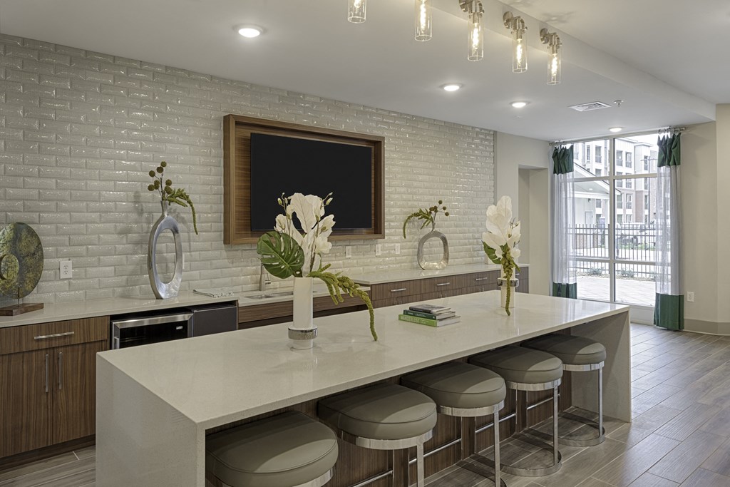 Clubhouse kitchen with island and seating, TV, mini fridge, and sink