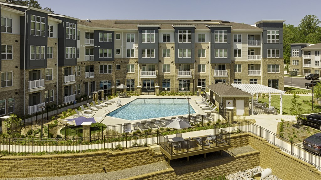 4-story apartment building surround community pool with chairs and hammocks