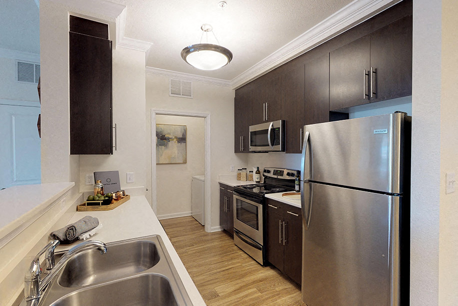Kitchen with dark cabinets, granite countertops, vinyl wood plank floors; open to living room; laundry room with washer and dryer