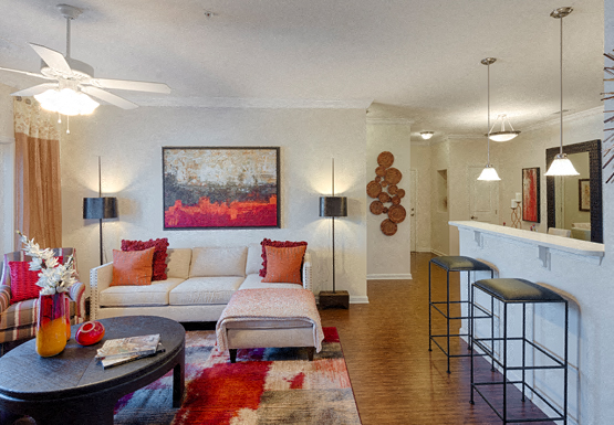 Living room with couch and chair; door to patio or balcony; ceiling fan