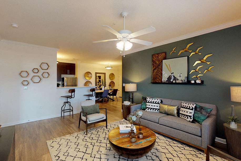 Living room with sofa and chair; ceiling fan; open to kitchen