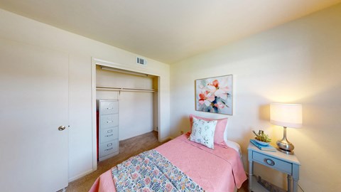 A bedroom with a pink bedspread and a bed with a floral pattern.