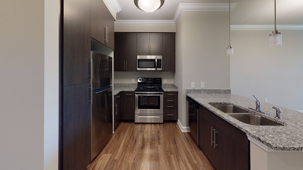 Kitchen with dark cabinets, granite countertops, vinyl wood plank floors; open to living room