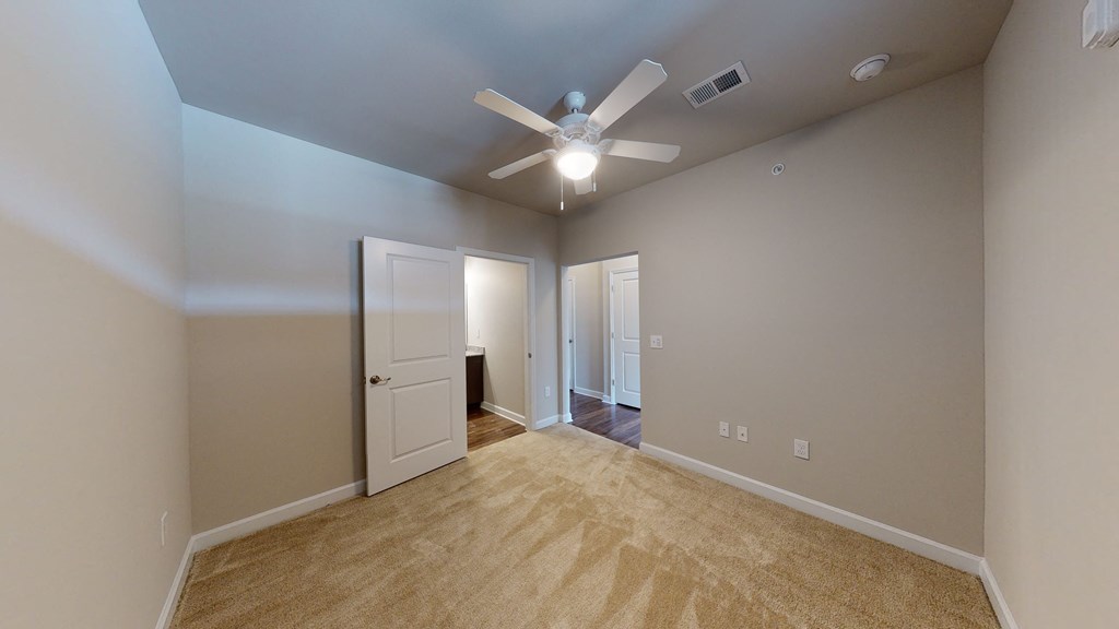 Bedroom with ceiling fan, carpet and door to bathroom