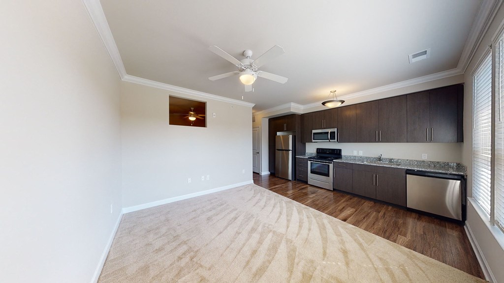 Living room with carpet open to kitchen with dark cabinets, vinyl plank floors