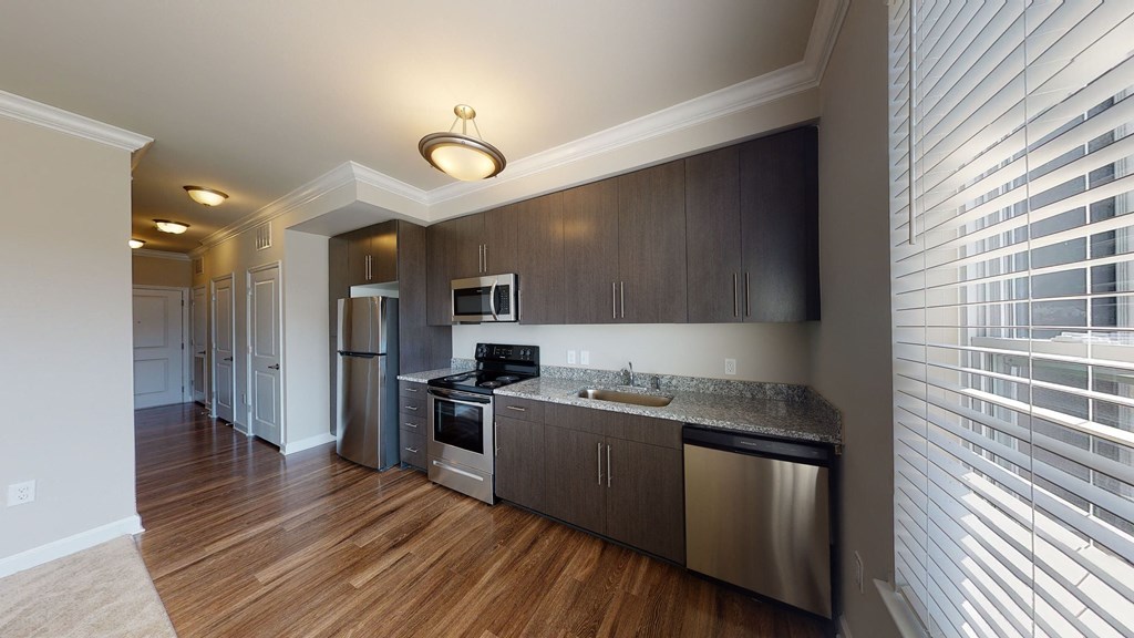 Kitchen with dark cabinets, granite countertops, vinyl wood plank floors; open to living room