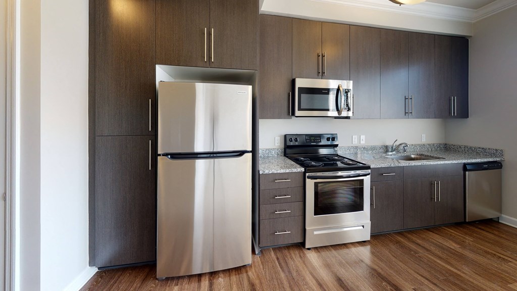 Kitchen with dark cabinets, granite countertops, vinyl wood plank floors