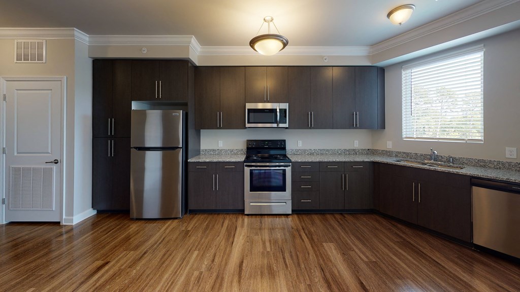 Kitchen with island, dark cabinets, vinyl floors and granite countertops