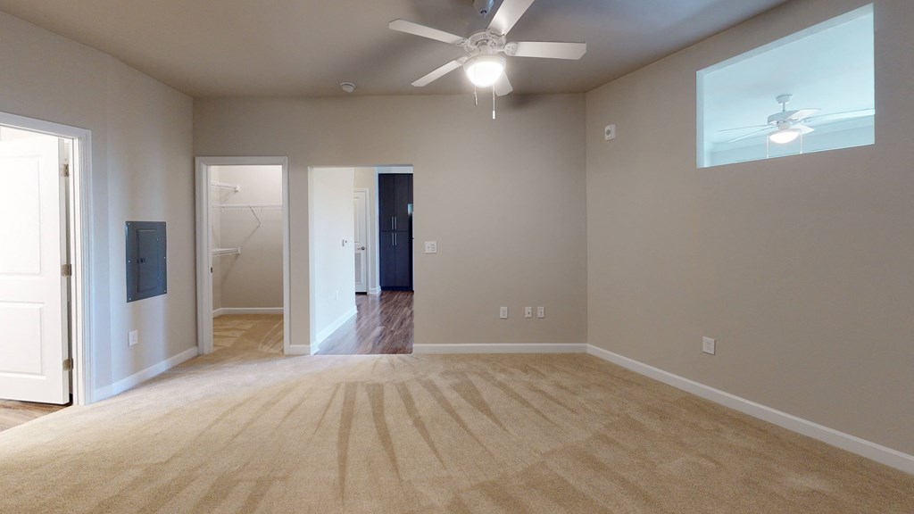 Bedroom with ceiling fan, carpet and door to bathroom