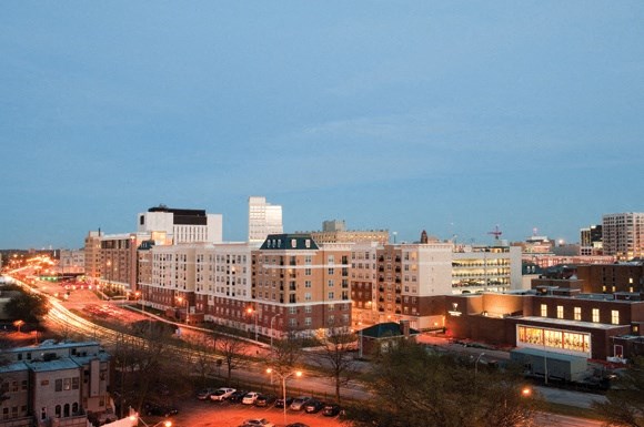 Belmont at Freemason apartment exterior at night; lights of the city and cars driving by