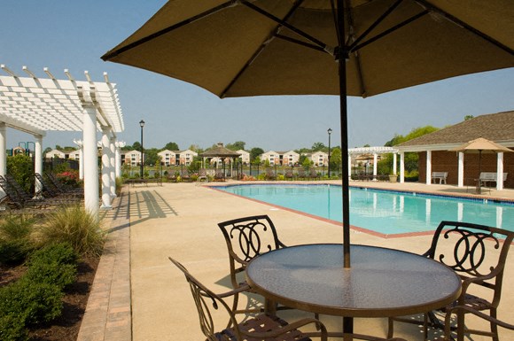 Table and chairs covered by umbrella; swimming pool; pergolas