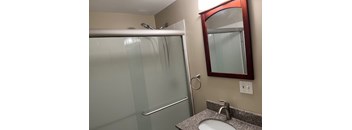 A bathroom with a sink, mirror, and shower.