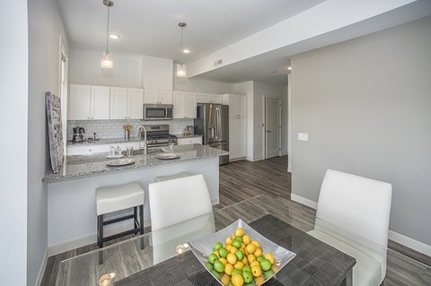 A modern kitchen with a glass table and white chairs.